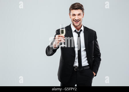 Smiling young businesman debout avec un verre de champagne et célébrer plus de fond blanc Banque D'Images