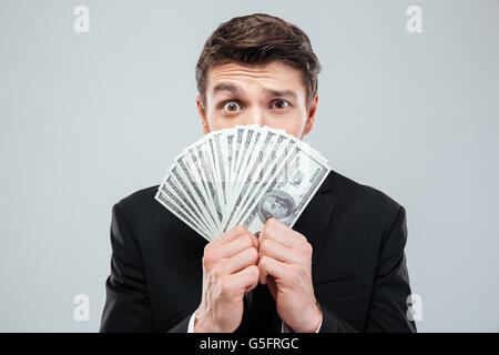 Jeune homme confus couvert son visage avec de l'argent sur fond blanc Banque D'Images