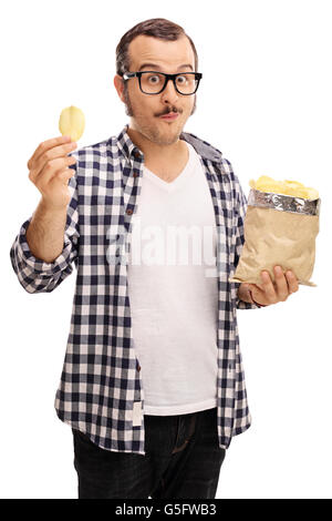 Shot verticale d'un jeune homme joyeux eating potato chips isolé sur fond blanc Banque D'Images