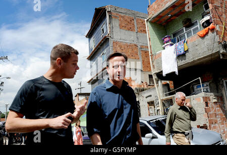 Le Premier ministre David Cameron se promène aujourd'hui dans Mare Favela au nord de Rio de Janeiro, où il a vu le projet Luta Pela Paz qui aide à éloigner les jeunes d'un crime de la vie et de la drogue et à pratiquer le sport. Le directeur de projet Luke Dowdney (à gauche) a montré au Premier ministre, qui est en visite de deux jours au Brésil, autour de la favela non pacifiée qui n'a aucun contrôle de police. Banque D'Images