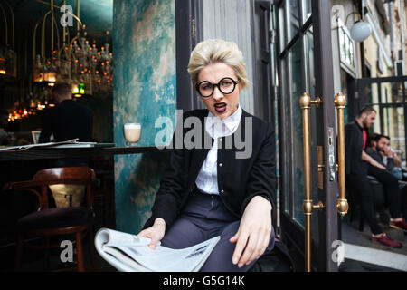Close-up portrait avec belle jeune fille en colère holding magazine en cafe Banque D'Images