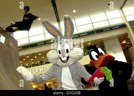 Un patineur en ligne montre ses tours au village de patins de Looney Tunes, Milton Keynes, regardé par les personnages de dessins animés Bugs Bunny (L) et Daffy Duck. Banque D'Images