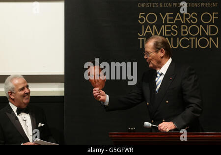 Sir Roger Moore tient un masque de l'actuel acteur James Bond Daniel Craig, avec l'encanteur Hugh Edmeades à la vente James Bond de Christie's, qui compte 50 ans, et des souvenirs offerts par The Bond Cast, à Christie's, à South Kensington, Londres. APPUYEZ SUR ASSOCIATION photo. Date de la photo: Vendredi 5 octobre 2012. Voir PA Story SALE Bond. Le crédit photo devrait se lire: Yui Mok/PA Wire Banque D'Images