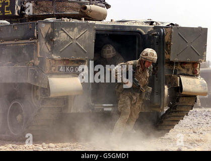 Les gardes irlandais de la 4e Brigade armée du 1er Bataillon de l'Armée britannique sortent de l'arrière d'un char de guerrier lors d'un exercice dans le désert d'Oman. Banque D'Images