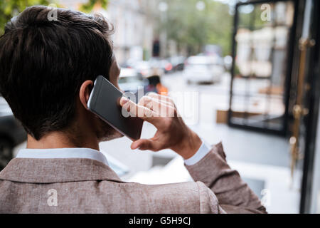 Vue arrière de young man talking on cell phone sur la ville de rue Banque D'Images