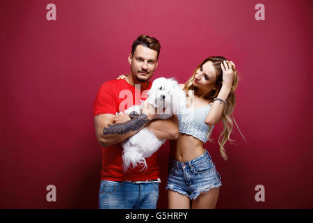 Couple avec chien blanc à l'encontre de l'arrière-plan lumineux Banque D'Images