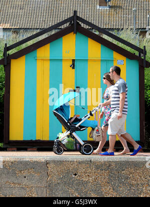 Un couple marche le long de la promenade à Clacton-on-Sea, Essex, comme ils profiter du beau temps. Banque D'Images