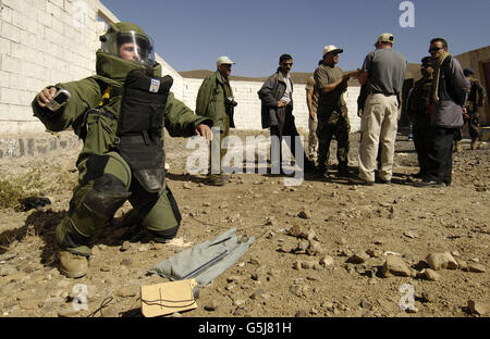Le Yémen des explosifs et munitions les membres de l'équipe regarder un Maître, vêtu d'une combinaison antibombe, détruire un engin explosif. Banque D'Images