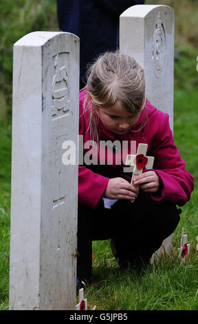 Un élève de l'école primaire sans nom de York place une croix de pavot sur une tombe de guerre dans le cimetière de York alors que le York Cemetery Trust et la Fulford British Legion ont organisé deux jours de visites pour plusieurs écoles de la région de York, comme ils l'ont expliqué au sujet du jour du souvenir et de l'histoire derrière lui. Banque D'Images