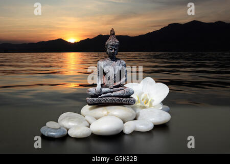Bouddha zen stone,blanc,fleurs d'orchidées et le fond de ciel Banque D'Images