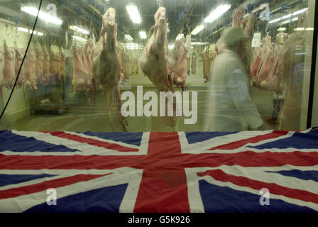 Un boucher passe devant des carcasses de veau accrochées au stand Gee & son du Smithfield Market, Londres. Le marché accueille le Festival national de la viande. Le Royal Smithfield Club décerne des trophées au chef du barbecue et au détaillant de viande de l'année. *...il y aura aussi des finales de carcasse avec les meilleurs produits du bétail de tout le pays, avec 375 carcasses de 120 roducteurs. Banque D'Images