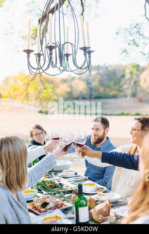 Friends toasting with wine at outdoor table Banque D'Images