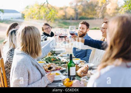 Friends toasting with wine at outdoor table Banque D'Images