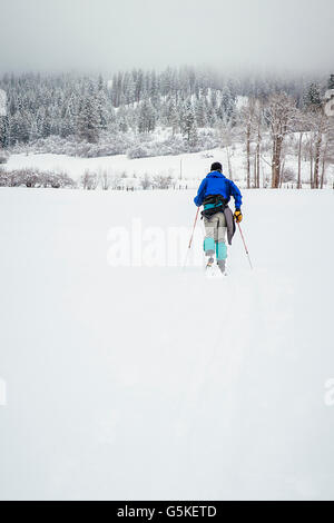 Caucasian woman ski de fond au champ neigeux Banque D'Images