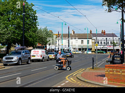 Man sur la mobilité scooter, crossing road à Fleetwood, Lancashire, England UK Banque D'Images