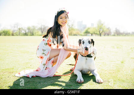 Chinese woman petting dog in field Banque D'Images
