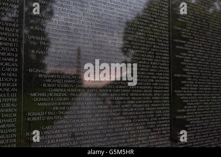 Le coucher du soleil et le Washington Monument se reflète sur les noms gravés dans le mur Vietnam Veterans Memorial à Washington, DC. Banque D'Images