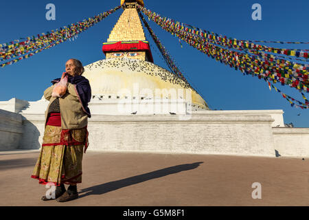 Femme en prière bouddhiste en face de Boudhanath, UNESCO World Heritage Site, Népal Banque D'Images