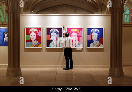 Le conservateur de l'exposition Royal Collection Trust David Westwood porte des portraits de la reine Elizabeth II d'Andy Warhol dans le cadre de l'exposition la Reine : portraits d'un Monach au château de Windsor. Banque D'Images