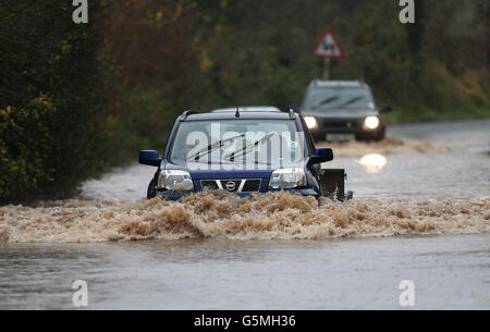 Les voitures traversent les inondations dans le village de Norton, près de Worcester, tandis que les automobilistes étaient invités à prendre plus de précautions sur les routes britanniques aujourd'hui, après les descentes de nuit qui ont amené certains conducteurs à abandonner leurs véhicules alors que les autoroutes publiques étaient inondées. Banque D'Images