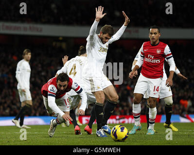 Le Santi Cazorla d'Arsenal (à gauche) va au sol à côté de Angel Rangel de Swansea City pendant le match de la Barclays Premier League au stade Emirates, Londres. Banque D'Images