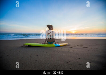 Caucasian woman sitting on surfboard on beach Banque D'Images