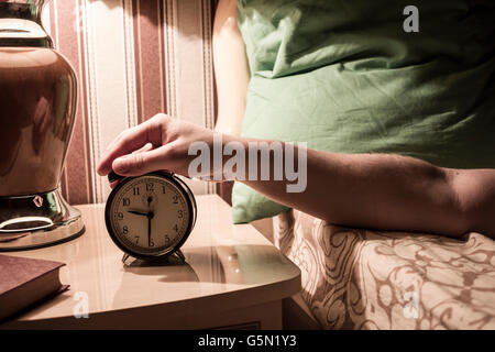 Caucasian man turning off alarm clock Banque D'Images