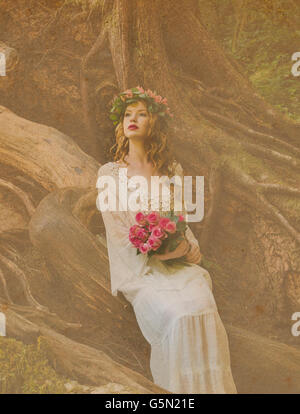 Caucasian woman holding bouquet of flowers in forest Banque D'Images