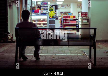 Homme assis sur le banc de la ville la nuit Banque D'Images