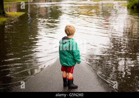 Young boy wearing flaques près de flood Banque D'Images