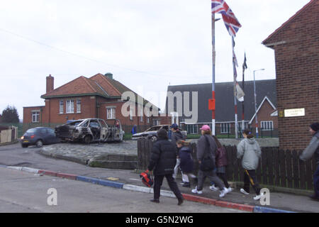 Les résidents loyalistes de la route d'Ardoyne marchent devant des voitures brûlées sur la route d'Ardoyne après des émeutes dans la région la nuit dernière. Une rangée de sentiers entre deux mères a déclenché la nouvelle flambée de violence sectaire qui a éclaté au point d'éclair nord de Belfast, a déclaré la police. * les officiers ont déménagé pour briser une confrontation après qu'une mère catholique sur son chemin pour recueillir sa fille de l'école primaire de Sainte Croix a été contestée par une femme protestante. C'est alors que des ennuis ont éclaté, se torgeant dans le pire désordre de rue de Belfast pendant plusieurs mois. Banque D'Images