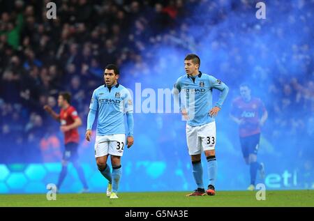 Une éruption bleue est repoussée dans l'arrière-plan comme Matija Nastasic (à droite) de Manchester City et Carlos Tevez déjecté après Manchester United a remporté le dernier vainqueur Banque D'Images