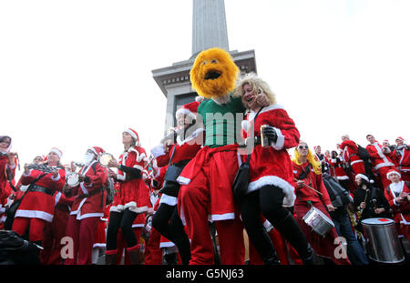 Les gens habillés comme le Père Noël prennent part à la foule éclair du Père Noël à Trafalgar Square, Londres. Banque D'Images