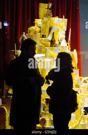 Les amateurs de shopping regardent une exposition de Noël dans la fenêtre de Selfridges, sur Oxford Street, dans le centre de Londres. Banque D'Images