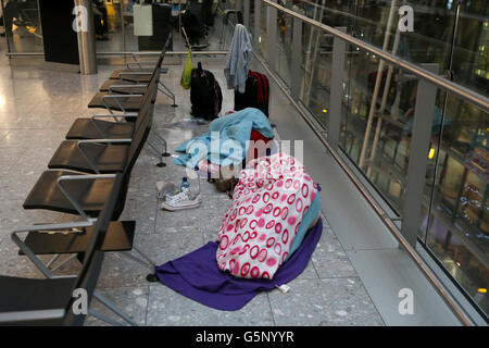 Les passagers dorment alors qu'ils se préparent à partir du terminal 5 de Heathrow, Londres, car les aéroports ont été contraints d'annuler des dizaines de vols à mesure que de la glace et du brouillard épais descendaient sur le Royaume-Uni pendant la nuit. Banque D'Images