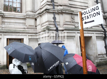 Londres, Royaume-Uni. 23 Juin, 2016. Gens portant des parapluies debout à côté d'un panneau "bureau de vote" qui pointe vers le bureau de vote où le premier ministre britannique David Cameron devrait voter pour le référendum Brexit, à Londres, Royaume-Uni, 23 juin 2016. Les Britanniques sont à voter sur l'opportunité de rester dans l'UE ou en sortir dans le cadre d'un référendum le même jour. Photo : MICHAEL KAPPELER/dpa/Alamy Live News Banque D'Images