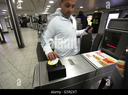 Un passager avec une Oyster Card utilisant les barrières tarifaires de la station de métro Oxford Circus de Londres. Banque D'Images