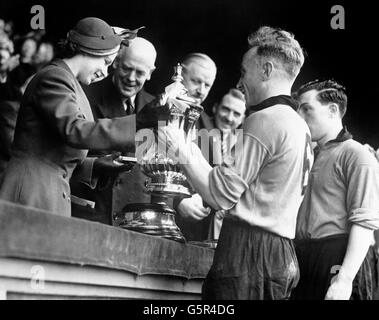 La princesse Elizabeth présente la coupe de l'association de football à Billy Wright, capitaine de Wolverhampton Wanderers après que Wolverhampton a battu Leicester City par trois buts à un dans la finale au stade Wembley. La princesse, le duc d'Édimbourg et le duc de Gloucester faisaient partie des 100,000 spectateurs du match. Banque D'Images