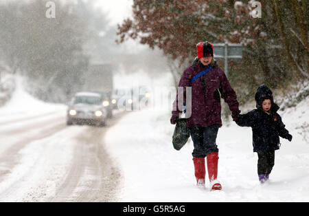 Une femme et un enfant marchent dans la neige dans le village de Norton près de Worcester, alors que le réseau de transport britannique a commencé à boucler aujourd'hui alors que la neige abondante a balayé le Royaume-Uni. Banque D'Images