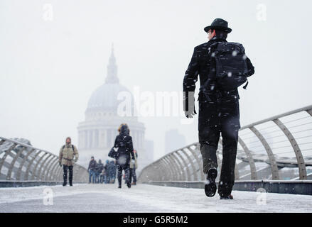 Des piétons traversent le Millennium Bridge, près de la cathédrale Saint-Paul, tandis que la neige tombe dans le centre de Londres. Banque D'Images