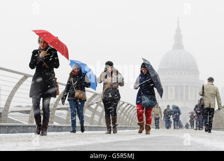 Des piétons traversent le Millennium Bridge, près de la cathédrale Saint-Paul, tandis que la neige tombe dans le centre de Londres. Banque D'Images