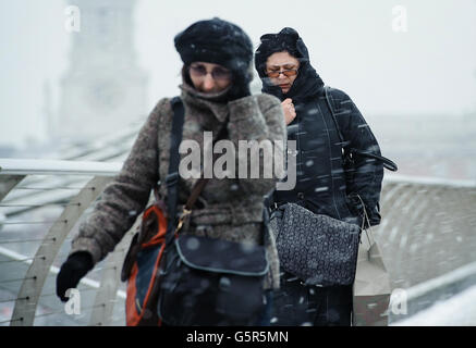 Des piétons traversent le Millennium Bridge, près de la cathédrale Saint-Paul, tandis que la neige tombe dans le centre de Londres. Banque D'Images