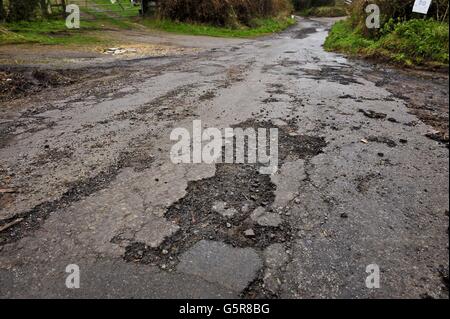 Une surface de route érodée sur une route de campagne dans le Gloucestershire autant de routes dans le Sud-Ouest ont besoin de travaux de réparation et de réfection après une année de fortes pluies et de récentes inondations, créant des nids-de-poule et des débris. Banque D'Images