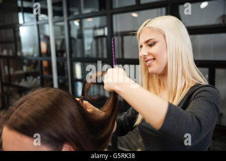 Pretty young woman getting une coupe de cheveux par une esthéticienne à parlour Banque D'Images