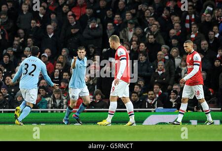 James Milner de Manchester City (au centre à gauche) célèbre le premier but de son équipe avec Coéquipier Carlos Tevez (à gauche) comme les joueurs d'Arsenal regardent sur abattu Banque D'Images