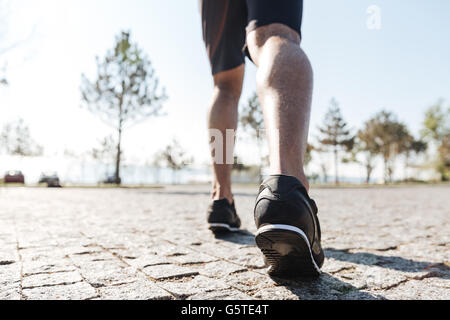 Vue arrière des jambes de l'homme sportif fonctionnant dans la ville Banque D'Images