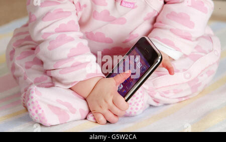 STOCKER bébé. Un bébé tenant un iPhone 3GS d'Apple. Banque D'Images
