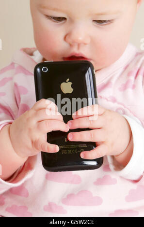 STOCKER bébé. Un bébé tenant un iPhone 3GS d'Apple. Banque D'Images