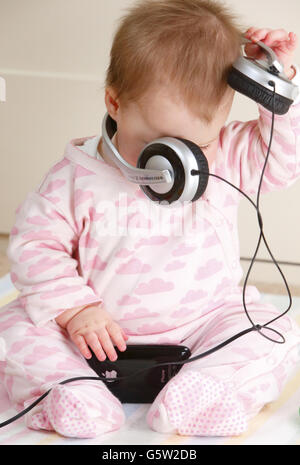 STOCKER bébé.Un bébé portant un casque et tenant un iPhone 3GS d'Apple. Banque D'Images