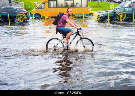 Man riding bicycle sur le chemin de la ville inondée à Kiev. Kiev est la capitale de l'Ukraine. Banque D'Images